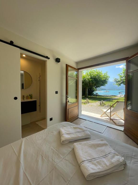 - une chambre avec un lit et 2 serviettes dans l'établissement Les Clapotis chambres pieds dans l eau lac d Annecy, à Angon