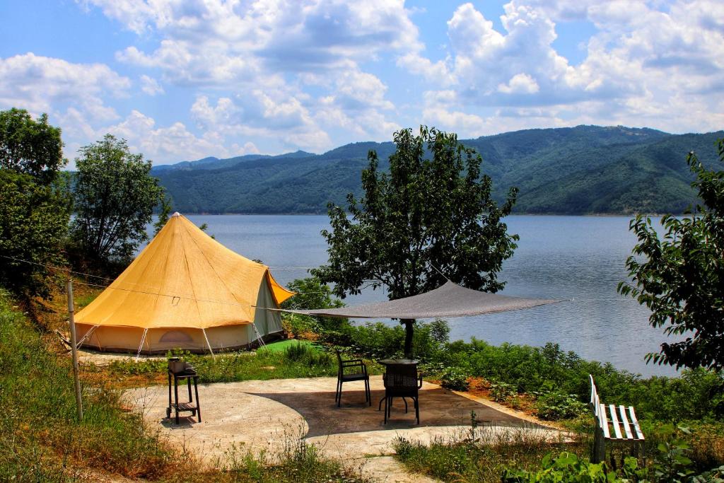 Staro Myasto的住宿－Lakeview Glamping，湖畔的帐篷和椅子