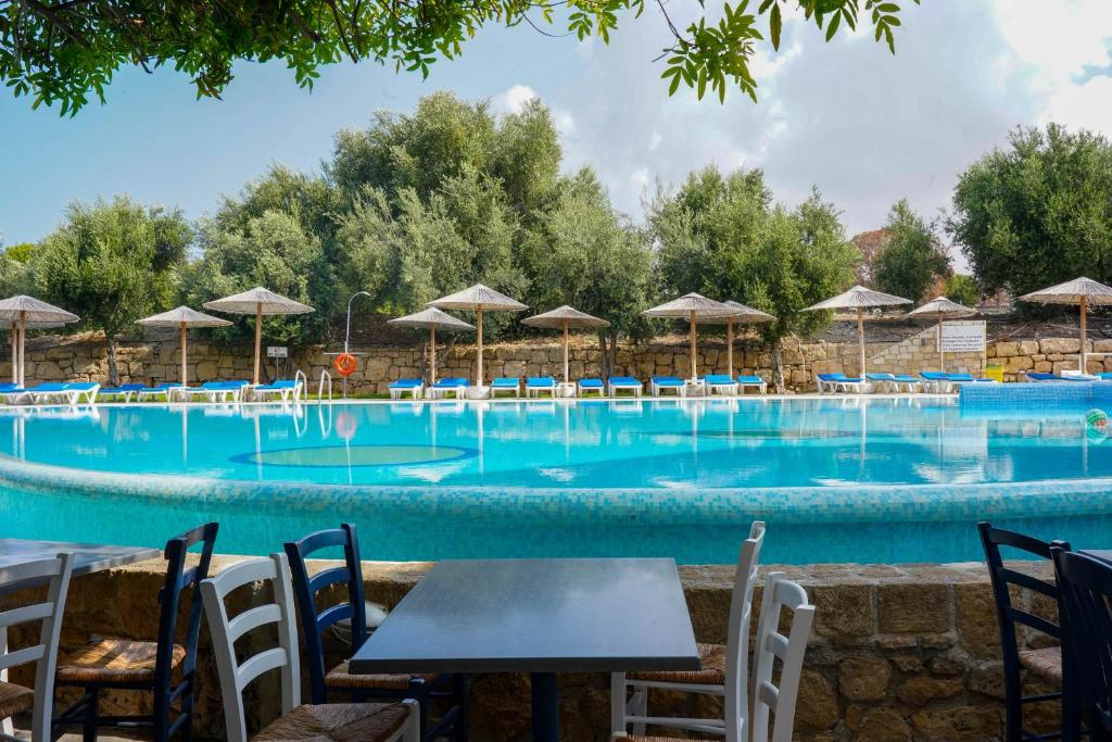 a swimming pool with tables and chairs and umbrellas at Basilica Holiday Resort in Paphos