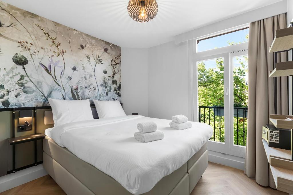 Dutch Design Hotel Vondelpark في أمستردام: غرفة نوم بسرير كبير عليها مناشف