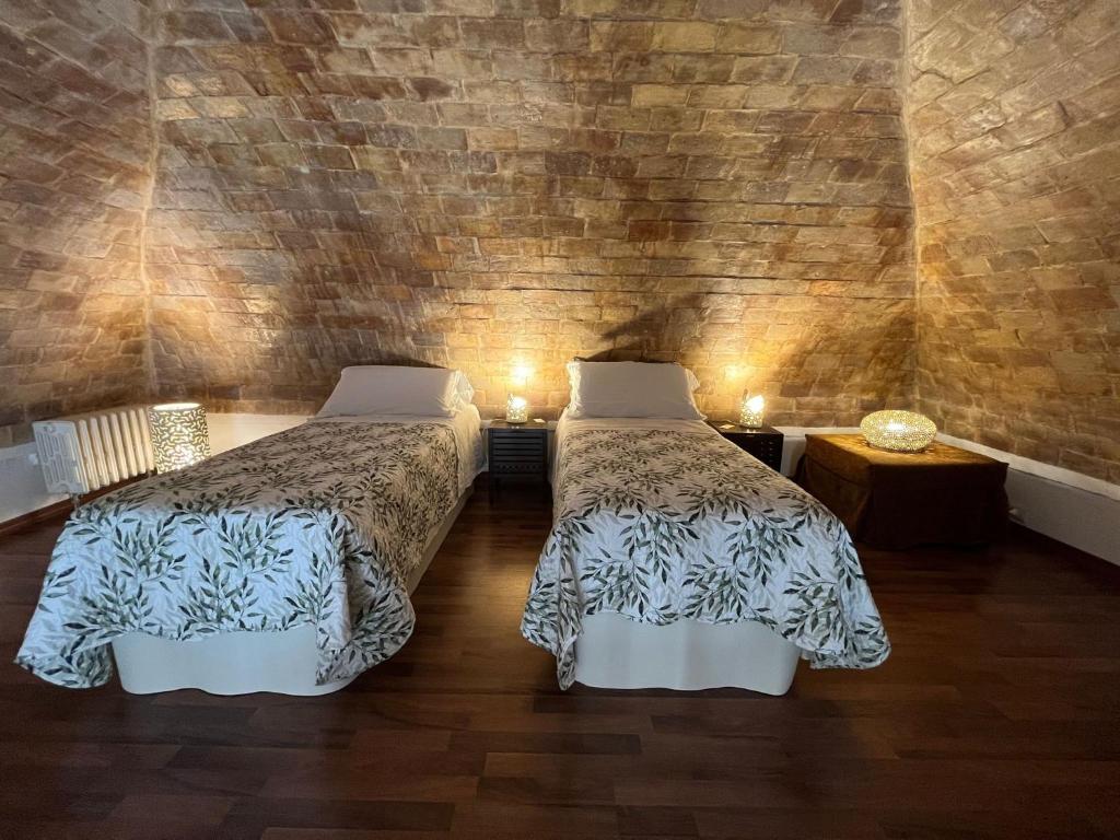 Un dormitorio con dos camas y una pared de ladrillo. en AL DUOMO, Dimora Storica, en Matera