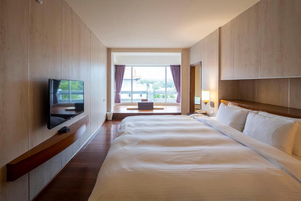 a hotel room with a large bed and a television at 水漾月明度假文旅 in Touwu