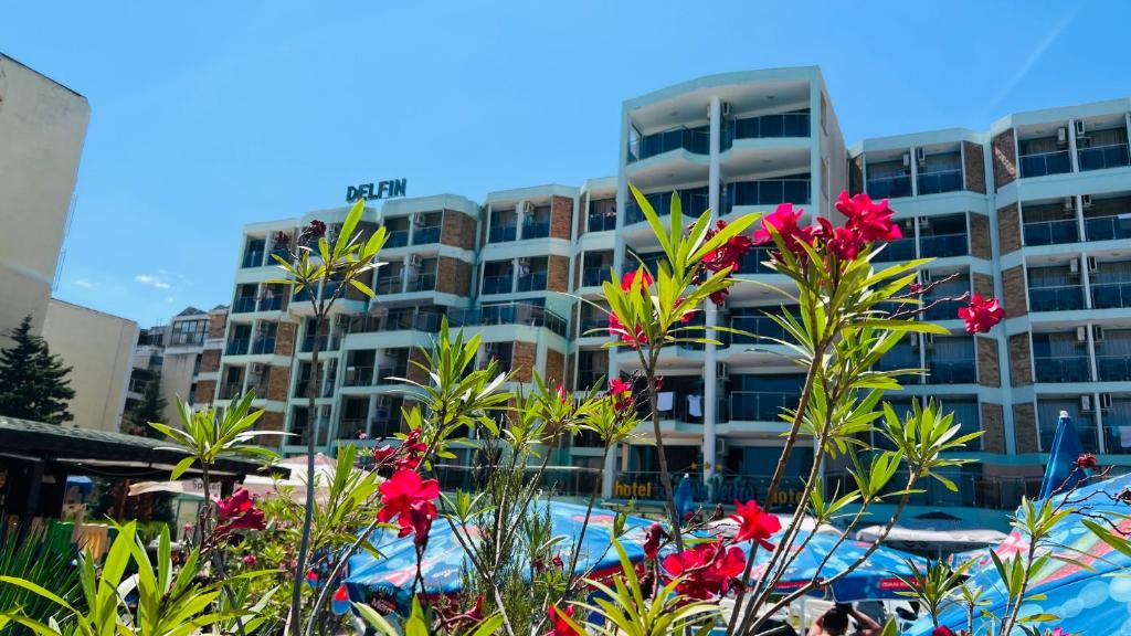 a hotel with red flowers in front of a building at Hotel Delfin - All Inclusive in Sunny Beach