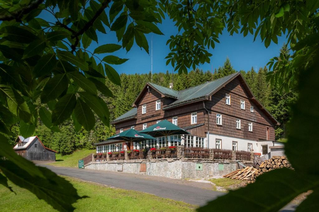 une grande grange en bois avec un restaurant sur une route dans l'établissement Lysečinská bouda, à Horní Maršov