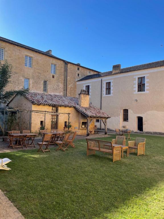 a group of tables and benches in the yard of a building at Auberge de Jeunesse HI Cadouin in Le Buisson de Cadouin