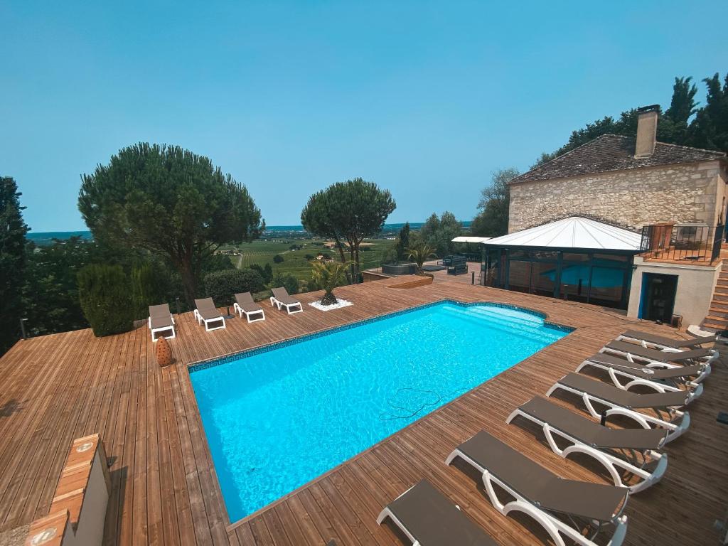 een zwembad met stoelen en een gebouw bij Villa Monbazillac, vue exceptionnelle, piscine, jacuzzi 10-16 pax in Monbazillac