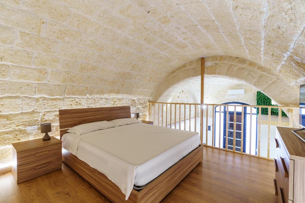 トラーニにあるScaringi Central Apartmentの石壁のベッドルーム1室(ベッド1台付)