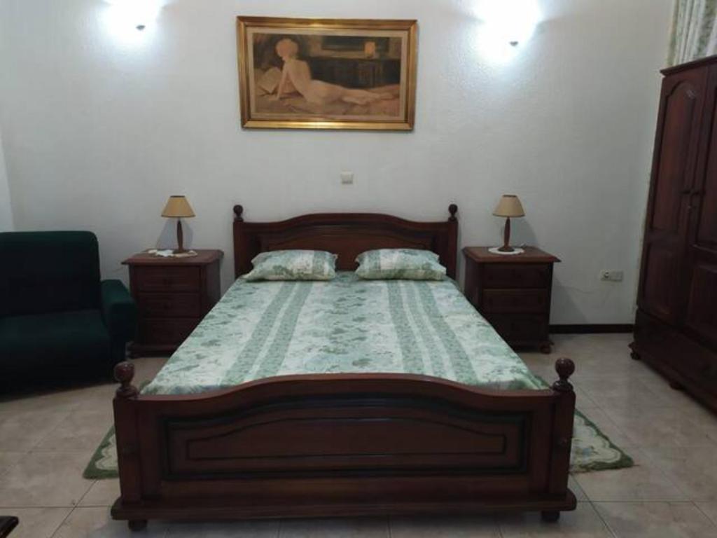a bedroom with a wooden bed with a painting on the wall at Cozy Room in Plateau in Praia
