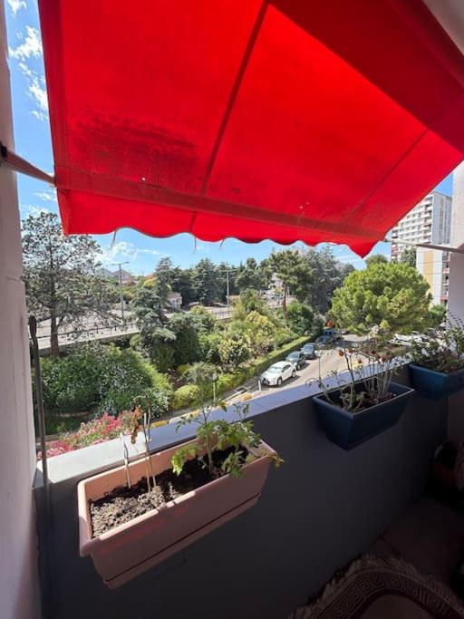 a red umbrella on a balcony with potted plants at Logement spacieux idéal famille in Marseille