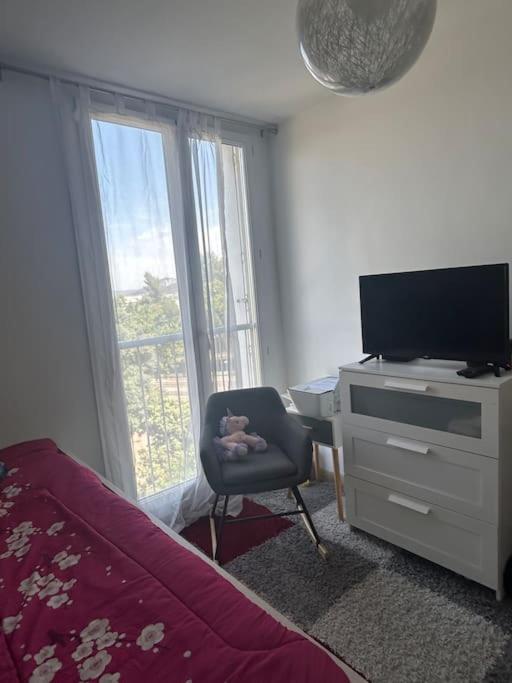 a bedroom with a bed and a chair and a television at Logement spacieux idéal famille in Marseille