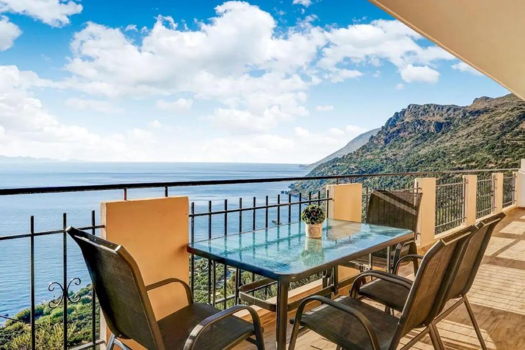 a table and chairs on a balcony overlooking the water at Kleio Studios in Ravdhoúkha