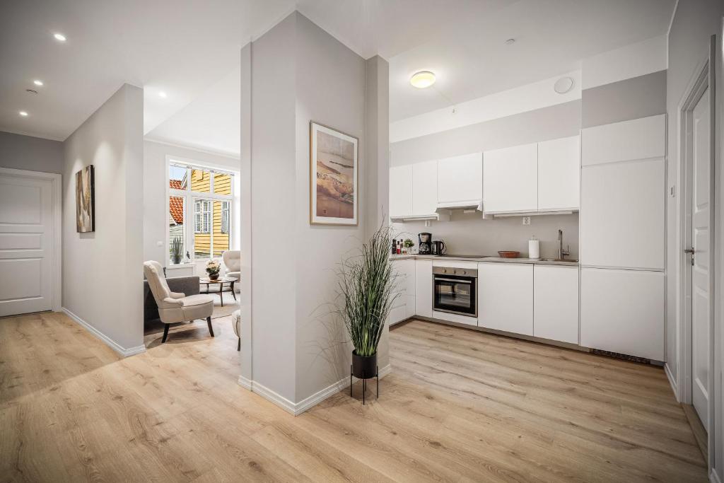 a kitchen with white cabinets and a living room at Corner Apartments in Bergen