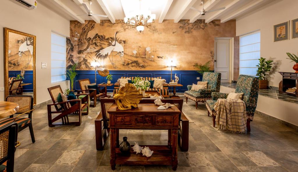 een lobby met tafels en stoelen en een muur met een muurschildering bij Elivaas Bludoor Luxe 5BHK Villa with Pvt Pool, Assagao in Marmagao
