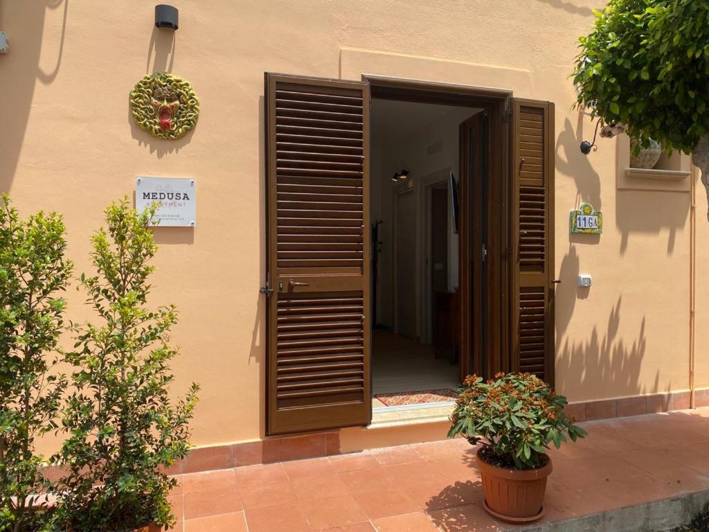 un ingresso di un edificio con porte in legno e piante di Medusa Apartment a Tropea