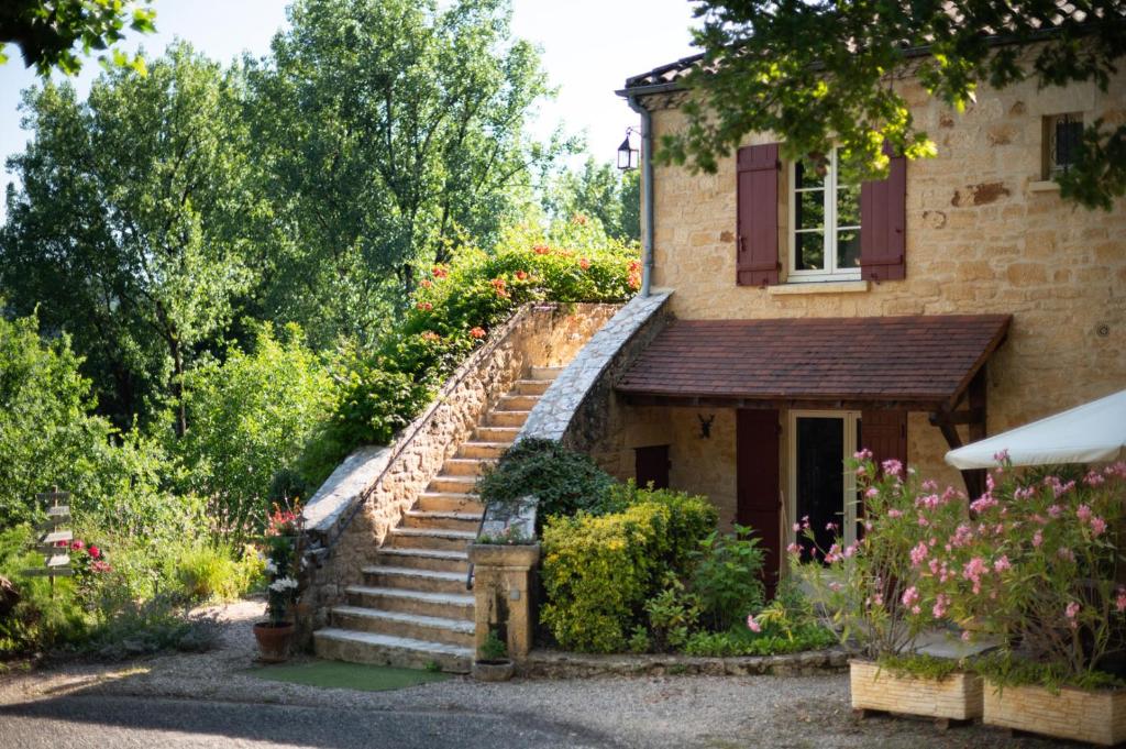 Un escalier en pierre mène à une maison fleurie. dans l'établissement LE CLOS VERSAILLES BEYNAC, à Beynac-et-Cazenac