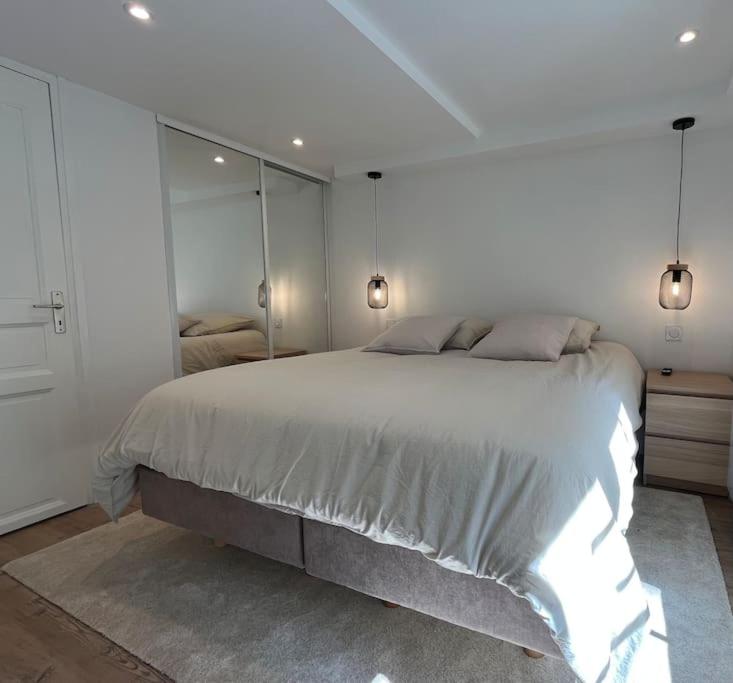 a white bedroom with a large bed and mirrors at Studio Cosy centre historique in Caen