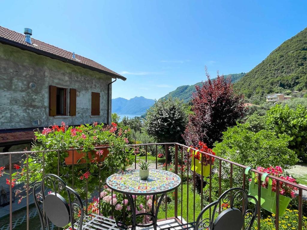 una mesa y sillas en un balcón con flores en Breva Loft tra gli ulivi ed il lago, en Bellagio