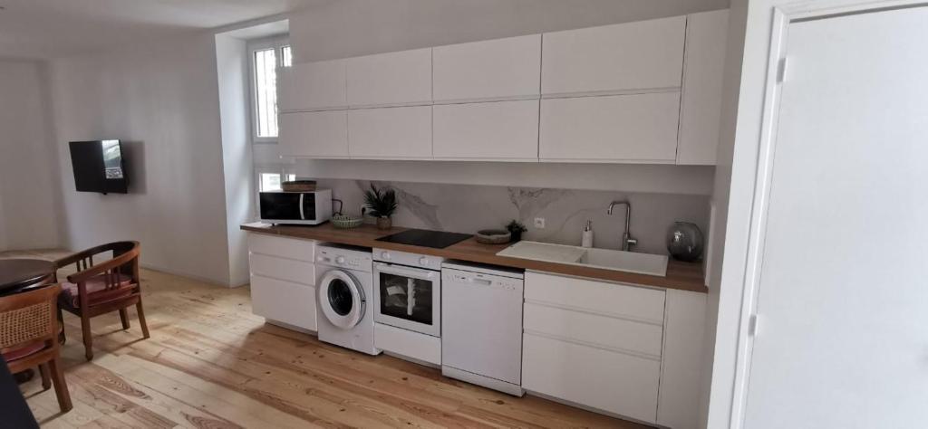 a kitchen with white cabinets and a washing machine at Duplex Dax in Dax