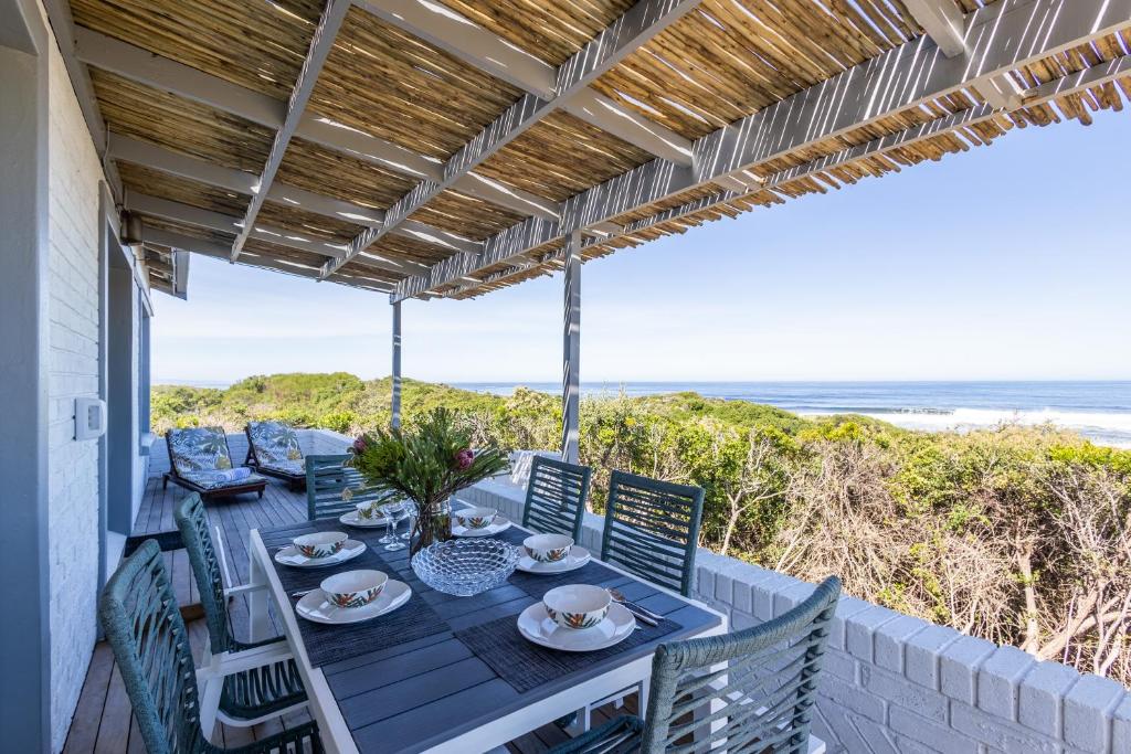 a table and chairs on a patio with the beach at Dunes Cottage in Plettenberg Bay