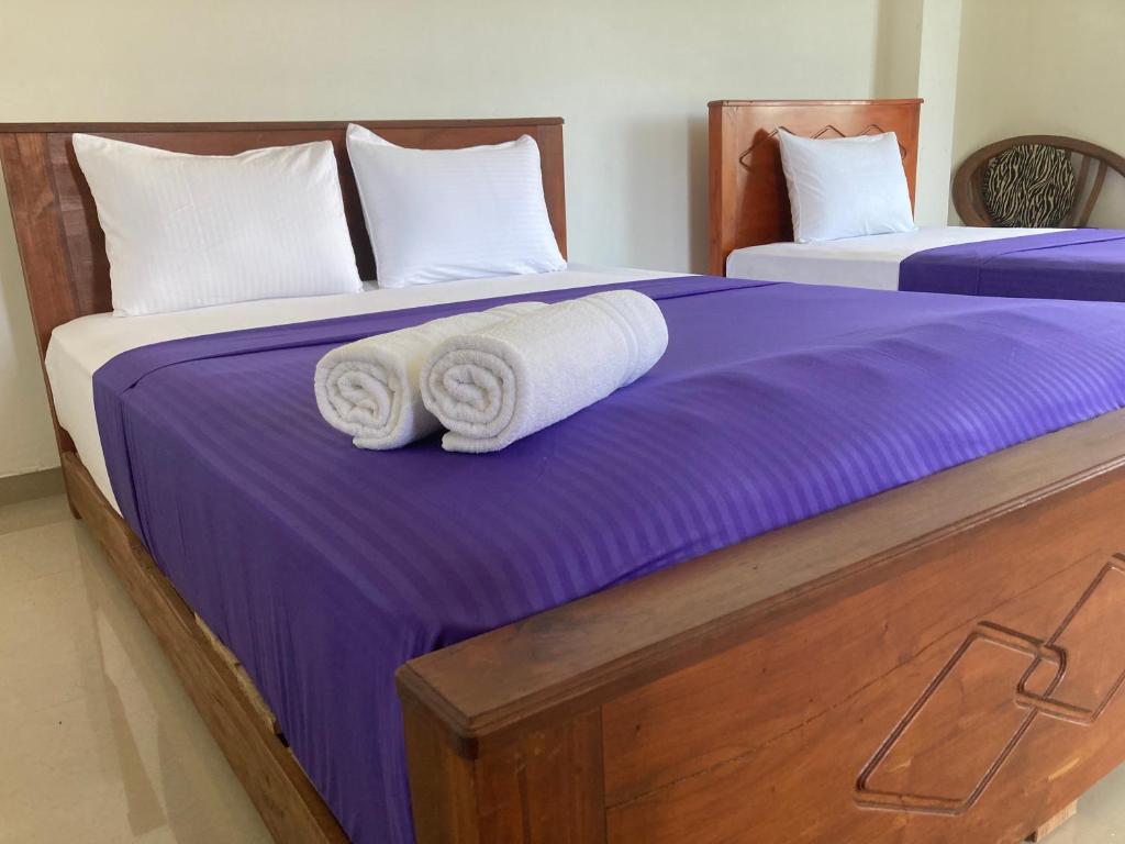 duas camas com lençóis roxos e toalhas em Springvalley Holiday Home em Badulla