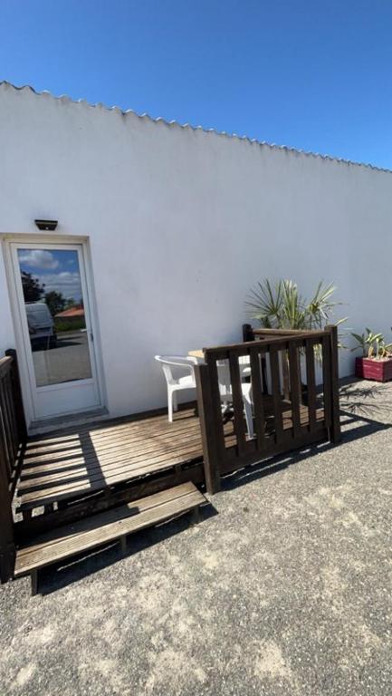 un banc en bois à côté d'un mur blanc avec une porte dans l'établissement les gites de la Bellezza, à Bois-de-Cené