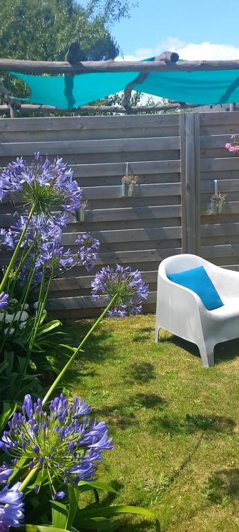 a garden with a white chair and purple flowers at Au gré des vents in Saint-Quay-Portrieux