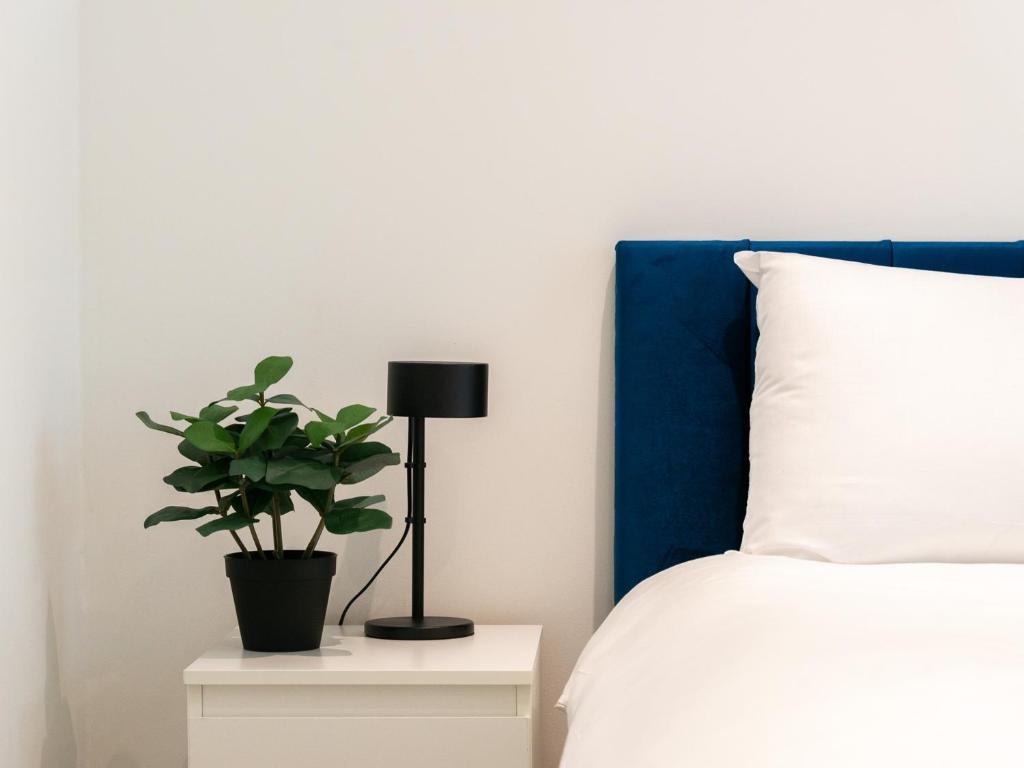 a bed with a black lamp and a plant on a night stand at Pass the Keys King s Cross Urban Oasis in London