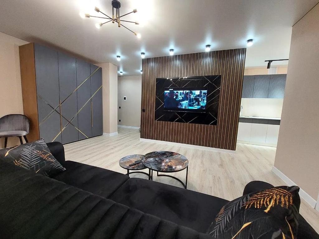 a living room with a black couch and a tv at Астана 18/1 in Ustʼ-Kamenogorsk