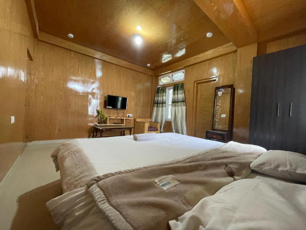 a bedroom with a large bed and a television at Vamoose Sonam Guest House Tawang in Tawang