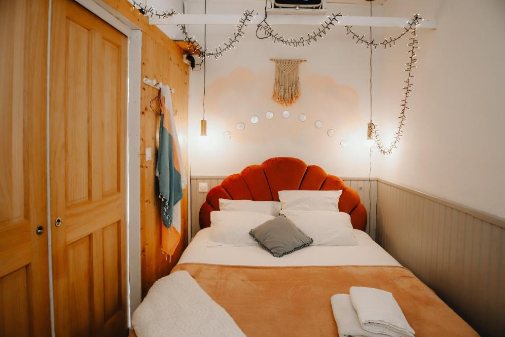 Una cama pequeña con cabecera naranja en una habitación. en Coquillages et crustacés, Netflix baignoire îlot chez Ivona Vacances, en Gujan-Mestras