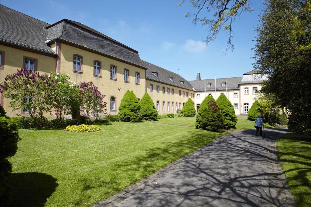 Kloster Steinfeld Gästehaus في Kall: شخص يمشي امام مبنى كبير
