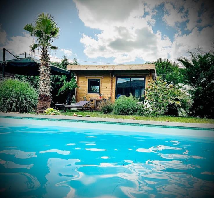 una casa con piscina frente a una casa en Chalet cosy avec piscine chauffée, en Beauregard-lʼÉvêque