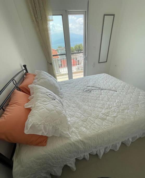 a bed with white sheets and pillows and a window at Διαμέρισμα στη Ναύπακτο in Nafpaktos