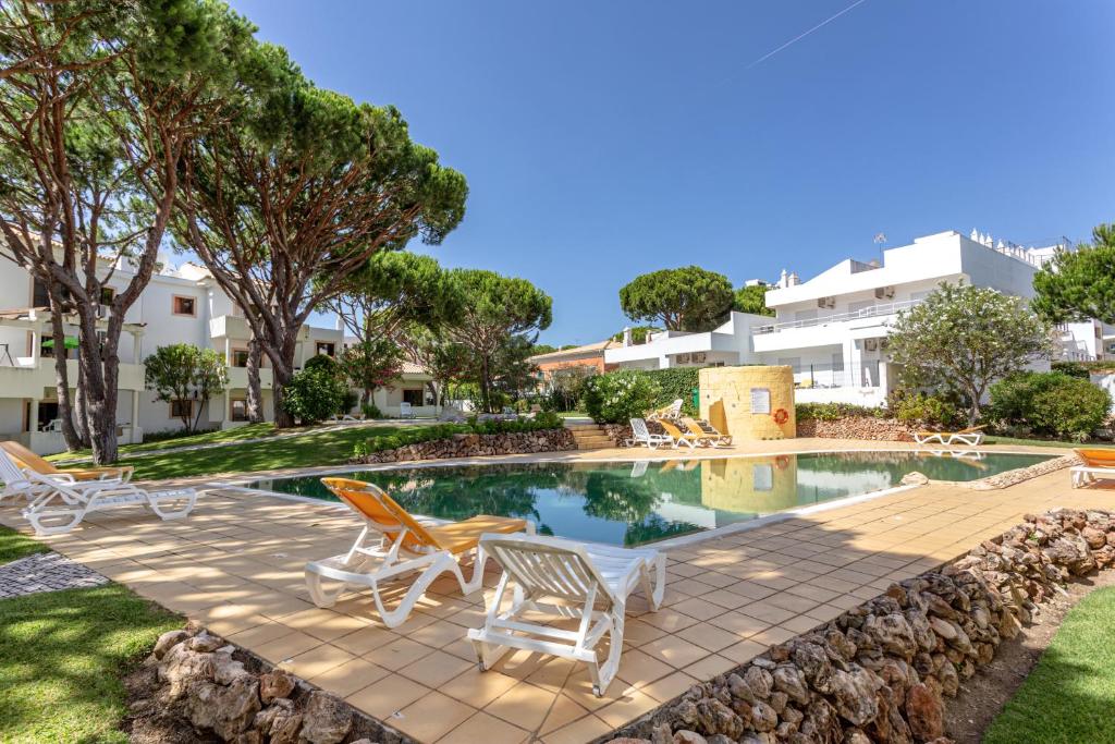 einen Pool mit Liegestühlen, eine Terrasse und ein Gebäude in der Unterkunft Fresh Sunny Flat with Pool & Terrace by Host Wise in Olhos de Água