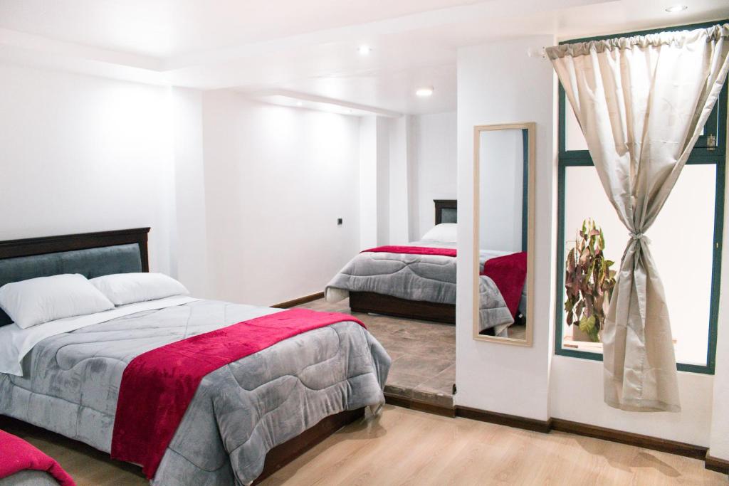 a bedroom with two beds and a mirror at El Capuli in Otavalo