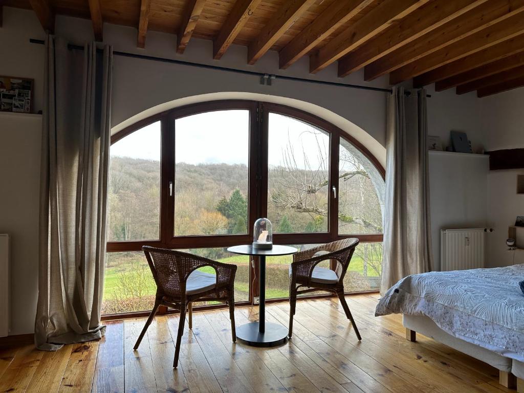 um quarto com uma mesa e cadeiras e uma grande janela em Les deux chambres au dessus de la colline em Namur