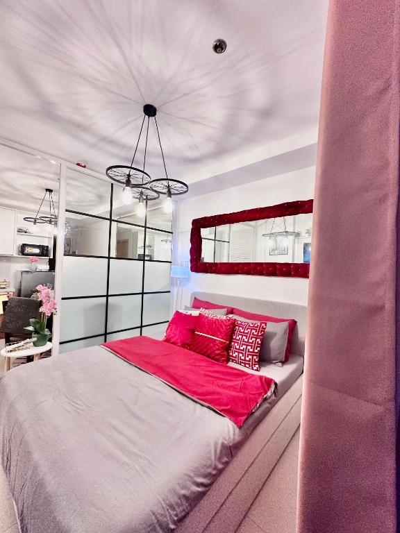 una camera da letto con un grande letto con cuscini rossi di Aesthetic One Bedroom Beside SM w Pool, Wifi and Netflix a Cagayan de Oro