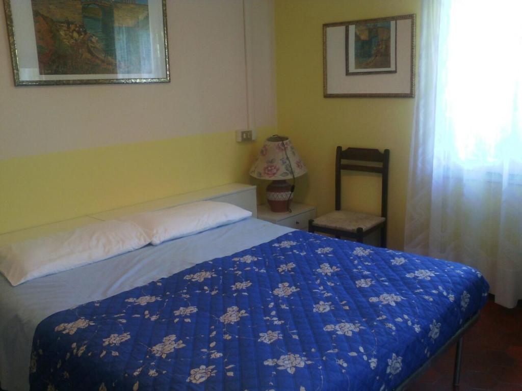 een slaapkamer met een bed met een blauw dekbed en een stoel bij Villa Montrona RR in Imola