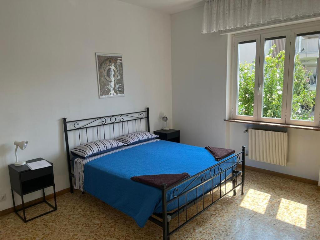 um quarto com uma cama azul e 2 janelas em Camere Giulia em Bérgamo