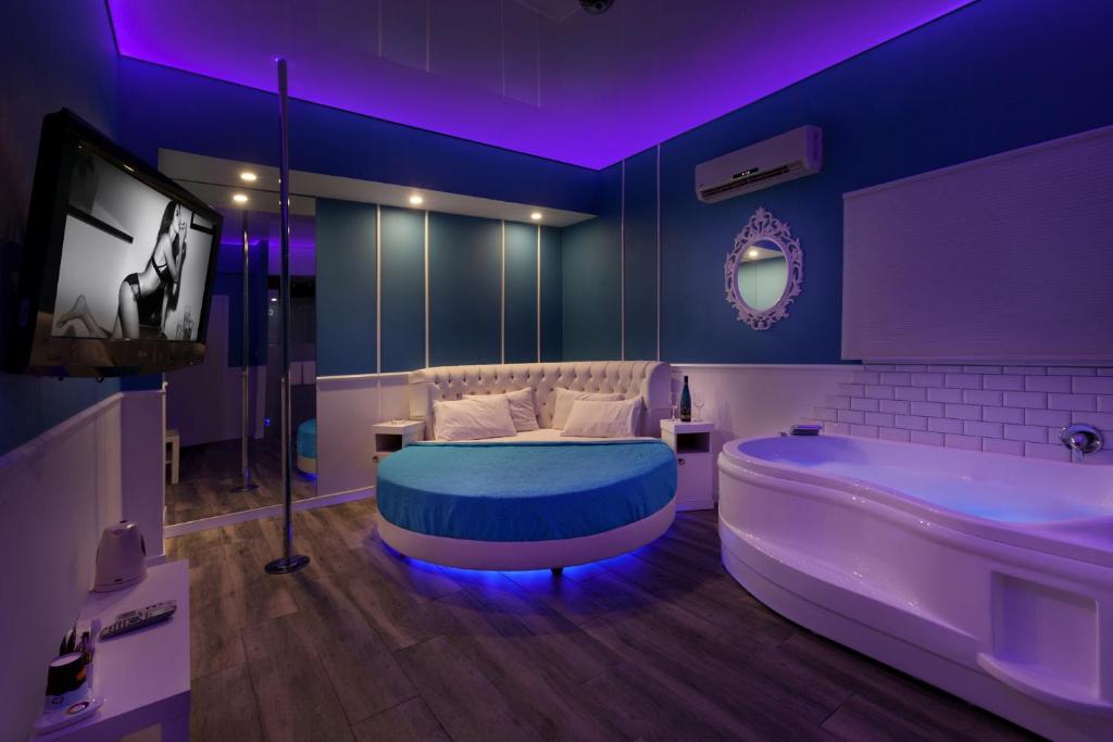 Metro Elegance Suites في Tel Binyamin: حمام مع حوض وسرير وتلفزيون