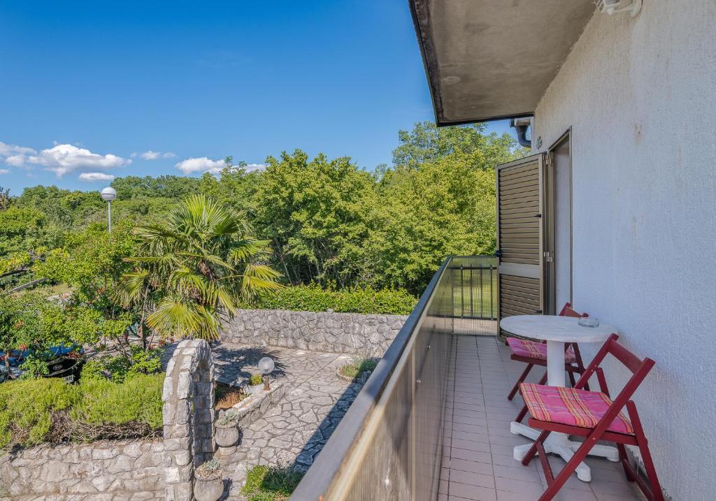 a balcony with two red chairs and a table at Apartment Moderna Soline in Dobrinj