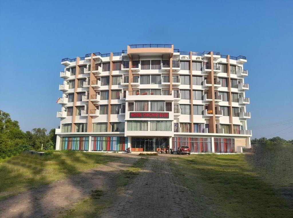 ein großes Apartmenthaus auf einer unbefestigten Straße in der Unterkunft Hotel Orchid Blue in Ināni