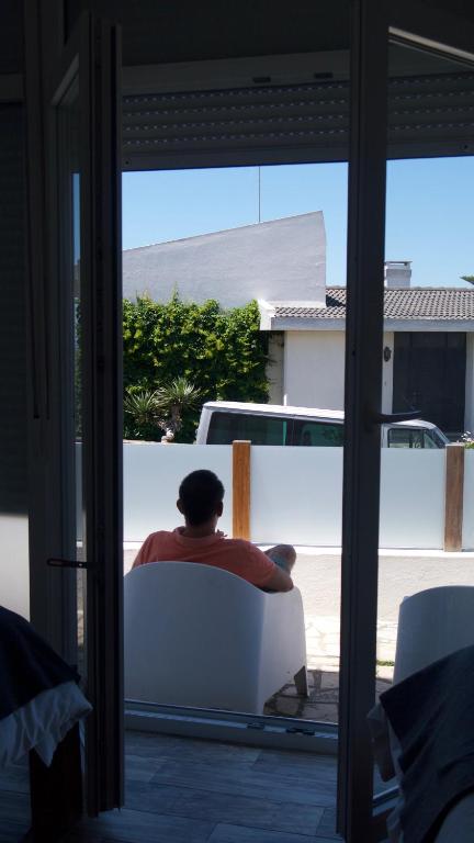 a man sitting in a white chair looking out a window at Hostel & Surfcamp 55 in Ericeira