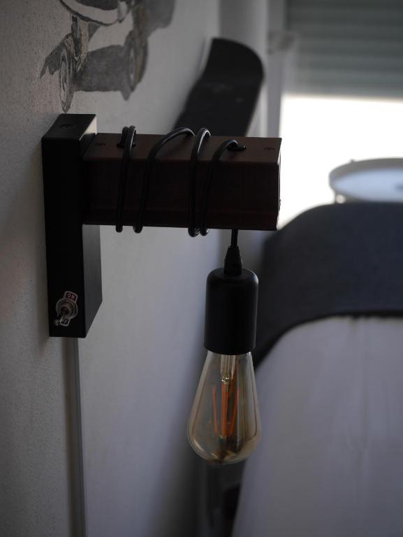 a black lamp hanging on a wall next to a bed at Hostel & Surfcamp 55 in Ericeira