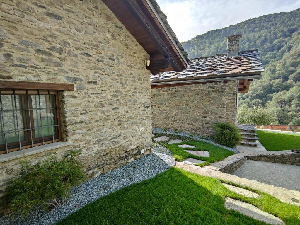 a stone house with a green yard next to a building at Ai Tetti Nuovi in Roccaforte Mondovì