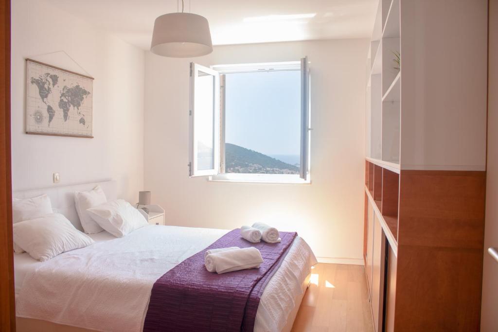 ein weißes Schlafzimmer mit einem Bett und einem Fenster in der Unterkunft Azure Horizon in Dubrovnik