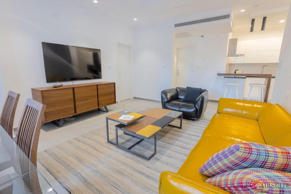 uma sala de estar com um sofá, uma televisão e uma mesa em Luxury Shenkin 2BR by Airsuite em Tel Aviv