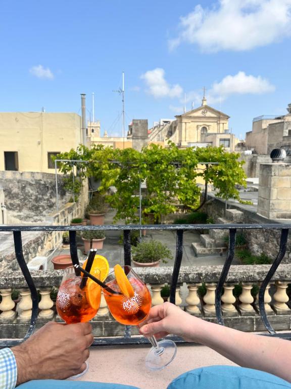 dos personas sosteniendo bebidas en un balcón en My Travel House, en Rabat