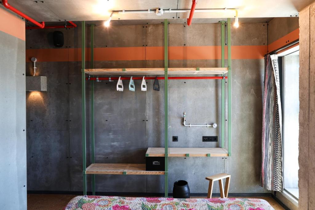 An industrial-style sleeping area with open shelving, hanging rails and a small stool.