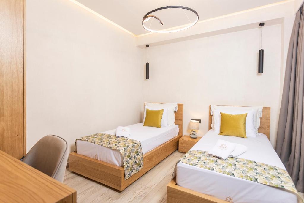 two beds in a room with a table and chairs at Kallithea Village hotel in Kallithea Halkidikis